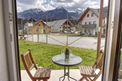 a glass table with two chairs and a window with a view at Apartma in studio Jerca ob Savi in Bohinj