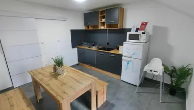 a kitchen with a wooden table and a refrigerator at Rooms Osmica- Videm pri Ptuju in Videm pri Ptuju