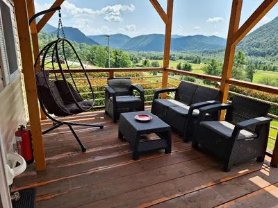 a porch with chairs and a swing and a table at Holiday HOUSE NEAR THE SOČA RIVER in Tolmin