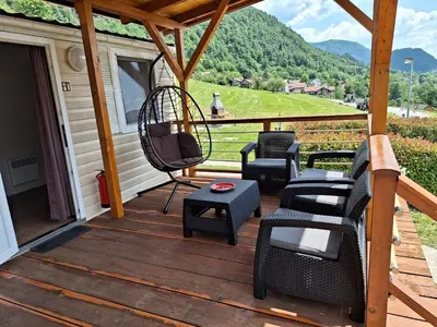 a patio with chairs and a swing on a porch at Holiday HOUSE NEAR THE SOČA RIVER in Tolmin