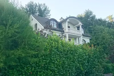 a white house with a balcony on top of a bush at Apartma Dolomiti in Ljubljana