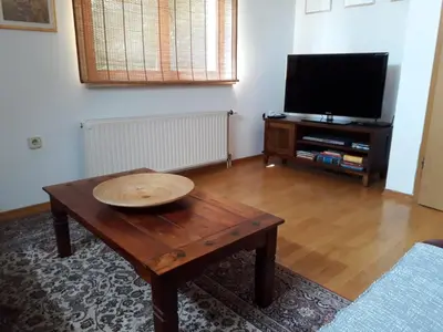 a living room with a wooden table and a flat screen tv at Apartma Dolomiti in Ljubljana