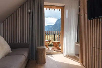 a living room with a couch and a view of a balcony at Hotel Majerca Superior in Bohinj