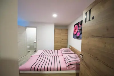 a bedroom with a bed with pink sheets on it at Guesthouse Urša in Preddvor