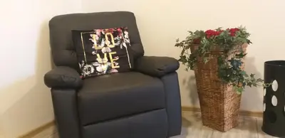 a black chair with a pillow on it next to a vase of flowers at Guesthouse Urša in Preddvor
