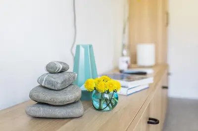 a counter with rocks and a vase of yellow flowers at Positive sport apartments in Kobarid