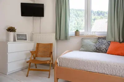 a bedroom with a bed and a chair and a window at Apartments Korošec in Bled