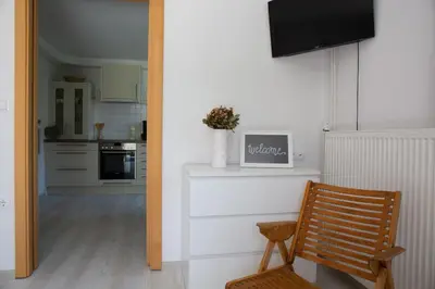 a kitchen with a wooden chair and a television on a wall at Apartments Korošec in Bled