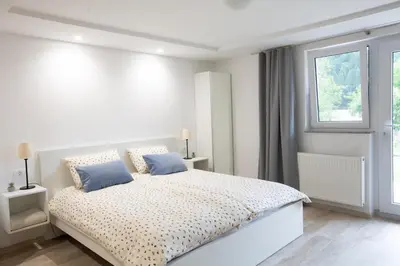 a white bedroom with a large bed with blue pillows at Apartments Korošec in Bled
