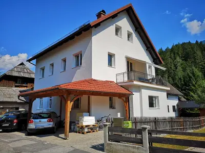 a white house with a car parked in front of it at Apartma EVA&MATIC in Kranjska Gora