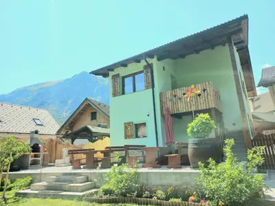 a house with a mountain in the background at Apartments Mojstrana - Kekec in Mojstrana