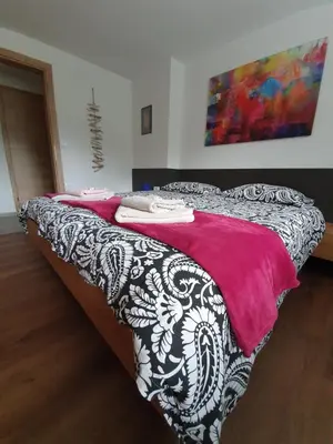 a bed with a red and white blanket on it at Apartments Mojstrana - Kekec in Mojstrana