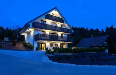 a large house with a lit up facade at night at Chilly apartment in Bled