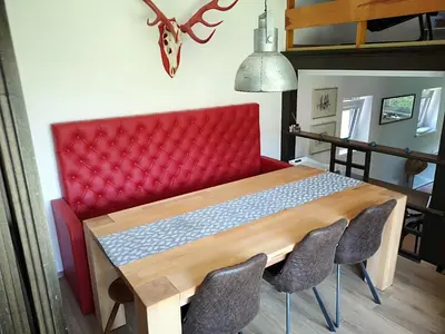 a dining room table with a red couch and chairs at Holiday House Red Deer in Preddvor