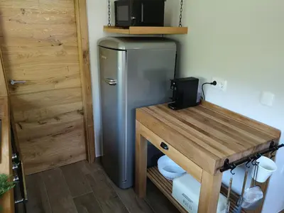 a refrigerator in a kitchen with a wooden table at Holiday House Red Deer in Preddvor