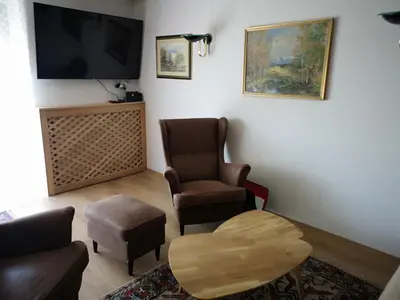 a living room with two chairs and a tv at Holiday House Red Deer in Preddvor