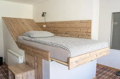 a bed in a room with a wooden headboard at Hiša Poljana Rooms in Prevalje