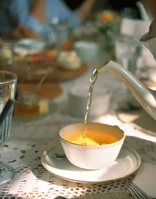 a cup of tea with a faucet pouring tea into it at Hiša Poljana Rooms in Prevalje