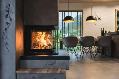 a fireplace in a living room with a table and chairs at Residence Novak Bohinj in Bohinj