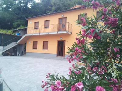 a large yellow house with a balcony and pink flowers at APARTMAJI MATAŽIN in Črni Kal