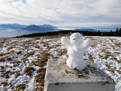 a snowman toy sitting on a block in a snowy field at Apartma Natura Kope in Šmartno pri Slovenj Gradcu
