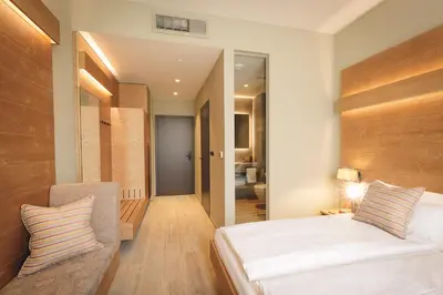 a bedroom with a bed and a chair in it at Boutique Hotel Sunrose 7 - Gourmet & SPA in Bohinj
