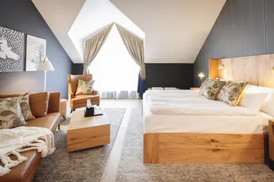 a bedroom with a large bed and a couch at Boutique Hotel Sunrose 7 - Gourmet & SPA in Bohinj