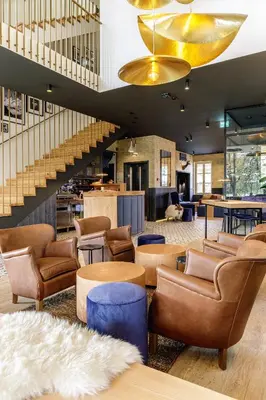 a lobby with chairs and tables and a staircase at Boutique Hotel Sunrose 7 - Gourmet & SPA in Bohinj
