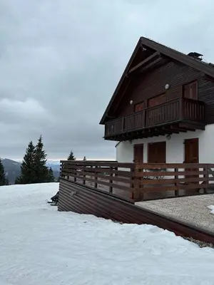 a wooden house with a fence and snow on the ground at Apartmaji Mara in Ribnica na Pohorju
