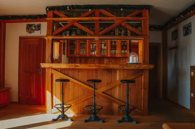 a wooden bar in a room with stools at Apartmaji Mara in Ribnica na Pohorju
