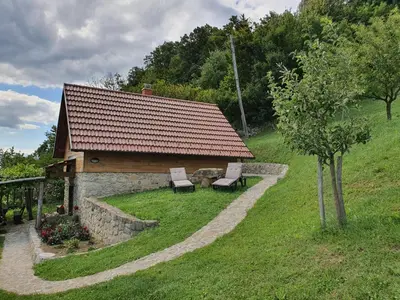 a stone building with two chairs and a tree at Relaxing Cottage Donacka Gora in Rogatec