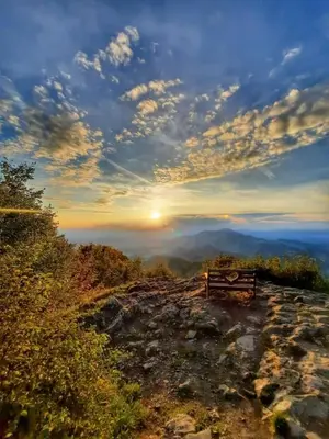 a bench sitting on top of a mountain with the sunset at Relaxing Cottage Donacka Gora in Rogatec