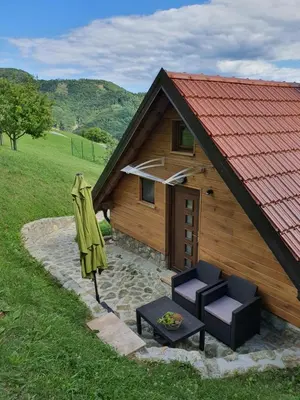 a small wooden building with two chairs and an umbrella at Relaxing Cottage Donacka Gora in Rogatec