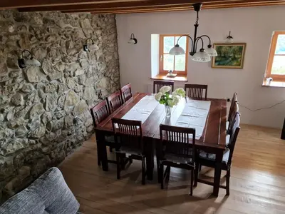 a dining room with a wooden table and a stone wall at Vacation House Donacka Gora in Rogatec