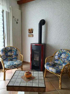 a living room with two chairs and a wood stove at Apartma MAELL 1 in Most na Soči