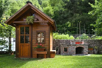 a small wooden shed with a stone oven in a yard at Apartma MAELL 1 in Most na Soči
