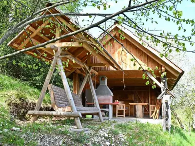 a log cabin with a porch and a porch swing at APARTMA JAKOPIČ in Zgornje Gorje