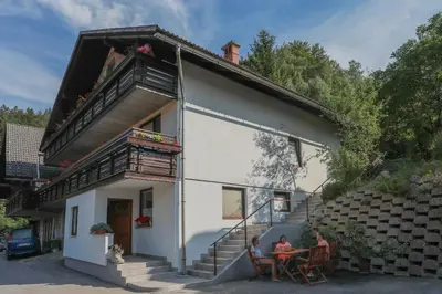 two people sitting at a table outside of a house at APARTMA JAKOPIČ in Zgornje Gorje