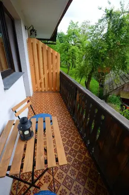 a wooden bench sitting on a balcony with a table at Apartmaji Pekovec Bohinj in Bohinj