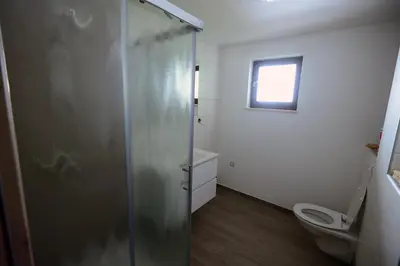 a bathroom with a shower and a toilet and a window at Apartmaji Pekovec Bohinj in Bohinj