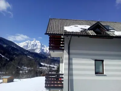 a building with snow on the roof and a mountain at JULIJA 3 SUNNY APPARTMENT in Kranjska Gora