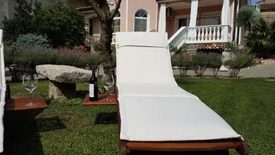 a white chair sitting in a yard with wine glasses at Wine cellar room in Vipava