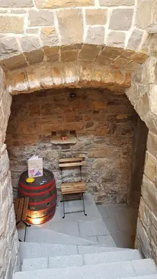 a room with a table and a bench in a stone wall at Wine cellar room in Vipava