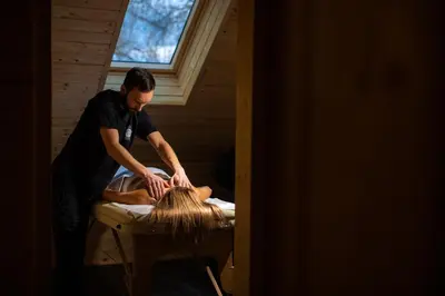 a man cutting a persons hair on a bed at Kozjanski dvor in Podčetrtek