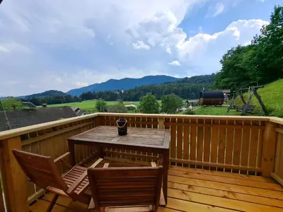 a wooden deck with two chairs and a table at PUŽMAN Farm Glamping in Radovljica