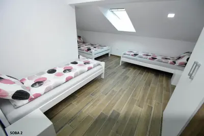 two beds in a room with wooden floors at Rooms pr zajčku in Tolmin