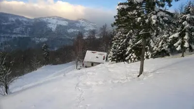 a snow covered hill with a house on top of it at Kopiše in Zoll