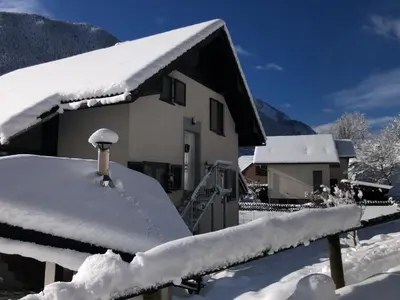 a house covered in snow next to a fence at SavaDolinka House ID 116O7O in Mojstrana