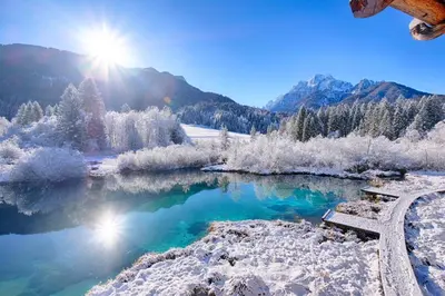 a lake covered in snow with the sun in the background at SavaDolinka House ID 116O7O in Mojstrana