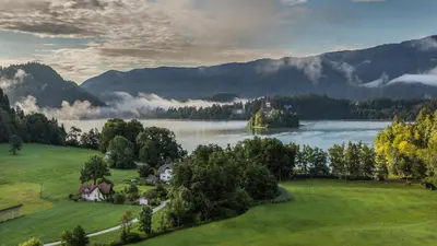 an island in the middle of a lake with mountains at Lake House Sebanc in Bled